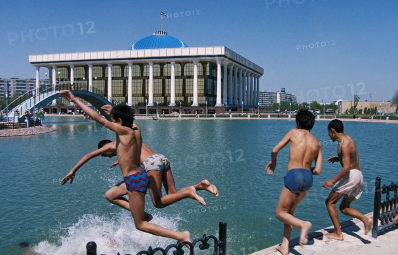 Boys swimming in a pool of a new park near the parliament building (in the background) in tashkent, uzbekistan, 1990s.