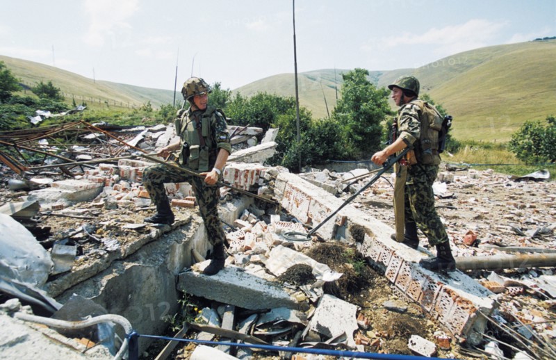 Russian peacekeepers using metal-detectors to search for unexploded bombs on the site of a yugoslavian ammunition depot destroyed in a nato air attack outside the slatina airport in pristina.