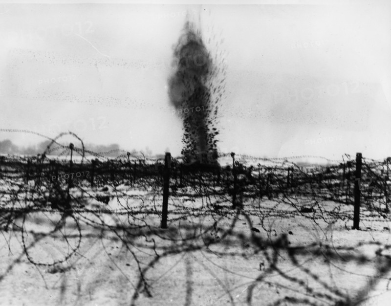 Shell bursting amongst the barbed wire entanglements.