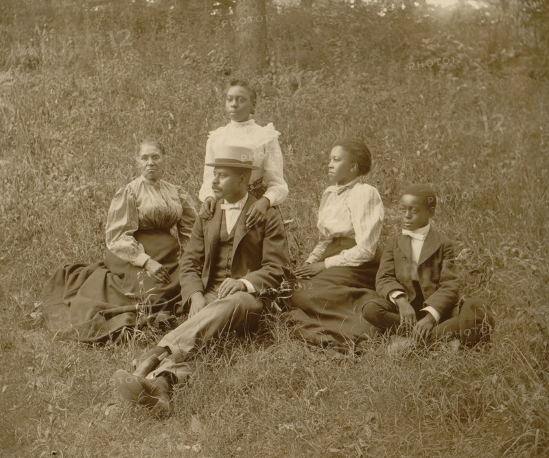 African American family posed for portrait seated on lawn