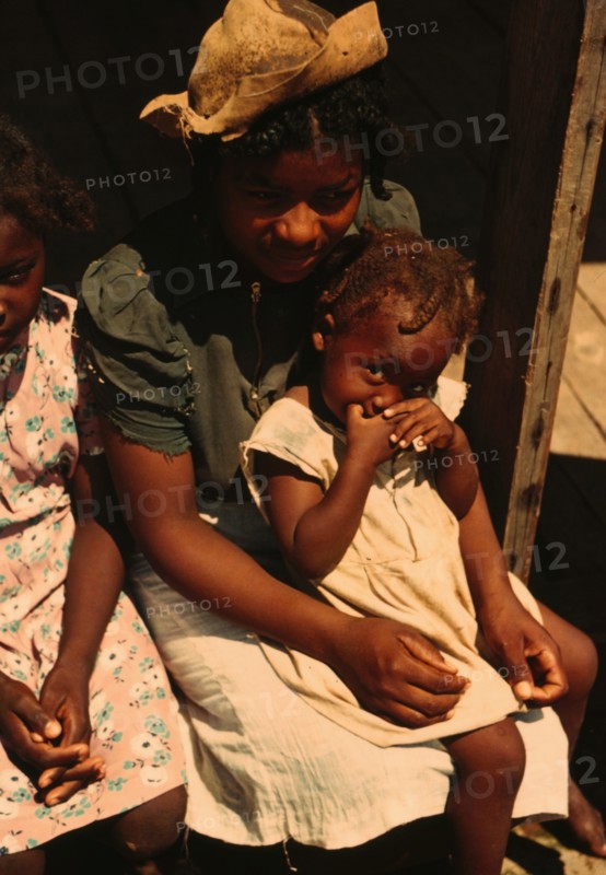 Three Negro children sitting on the porch of a house