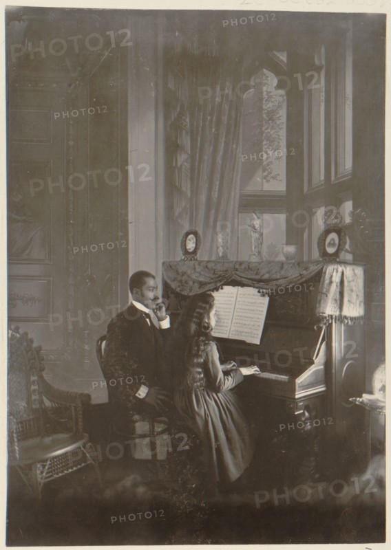 African American man giving piano lesson to young African American woman