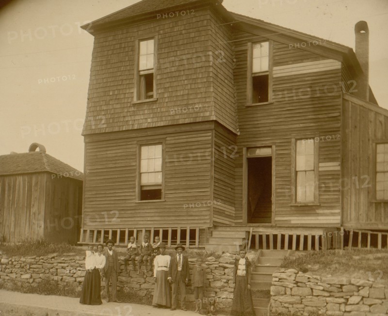 African Americans standing on sidewalk in front of house in Georgia