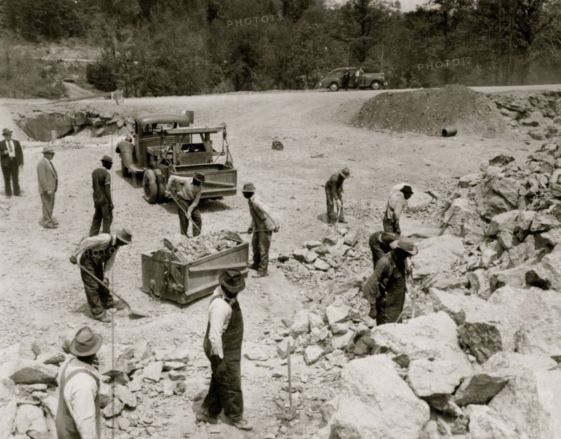 Prisoners breaking up rocks at a prison camp or road construction site