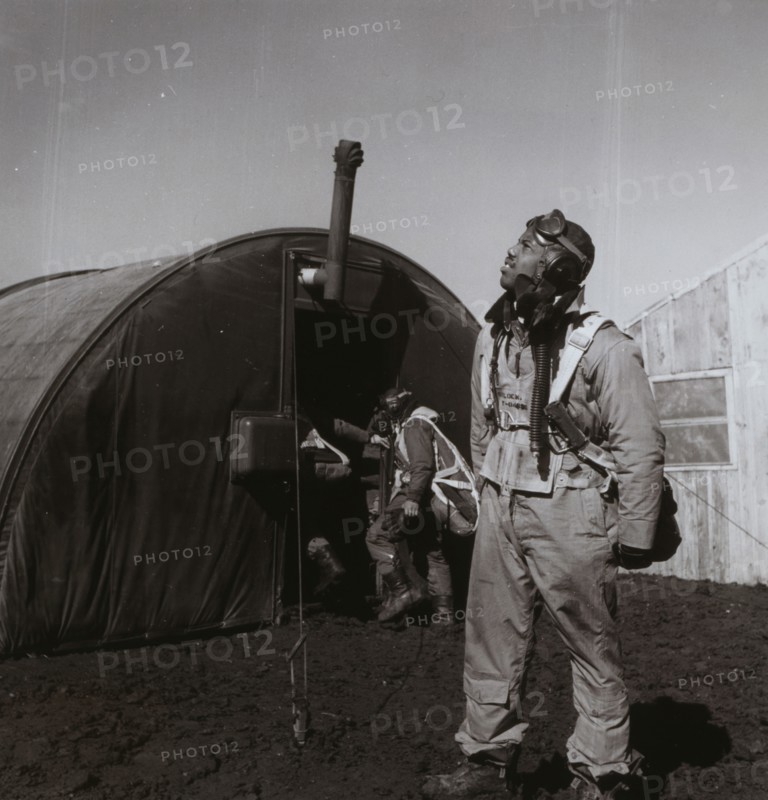 Black fighter pilot series--pilot with parachute room in background, Ramitelli, Italy