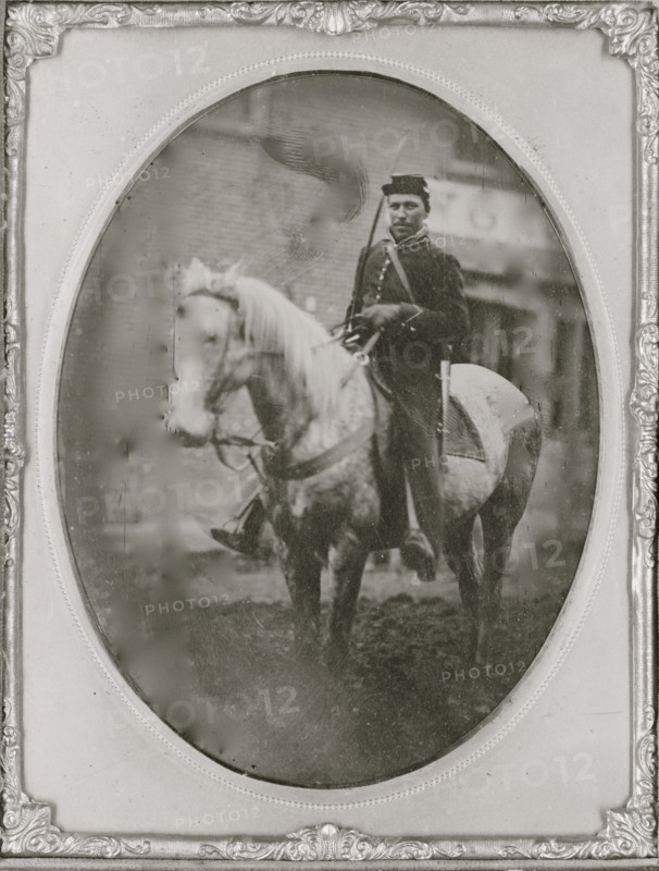 Unidentified African American soldier seated on horseback, facing left.