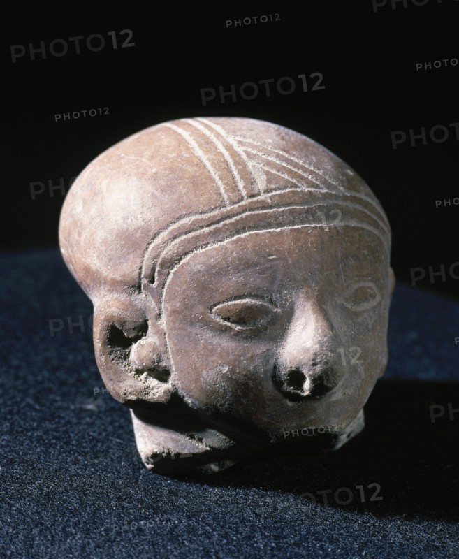 Clay head with eyes and ornaments.