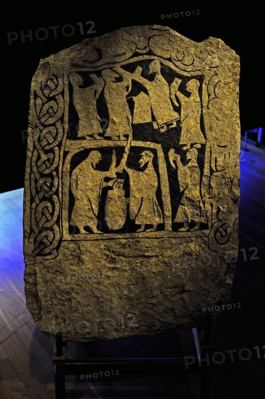 Runic Stone. Men with drinking horns and two men fighting with swords.