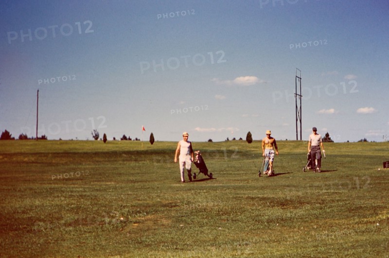 Men on the fairway of a golf course carrying their golf bags circa 1957-1960.