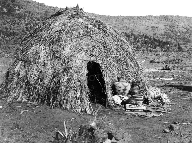 Edward S. Curits Native American Indians - Rounded structure made out of grass, with baskets in front circa 1903.