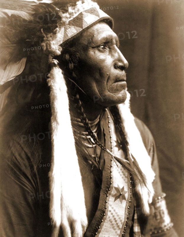 Edward S. Curtis Native American Indians - Raven Blanket, wearing several necklaces and warbonnet with ermine streamers circa 1910.