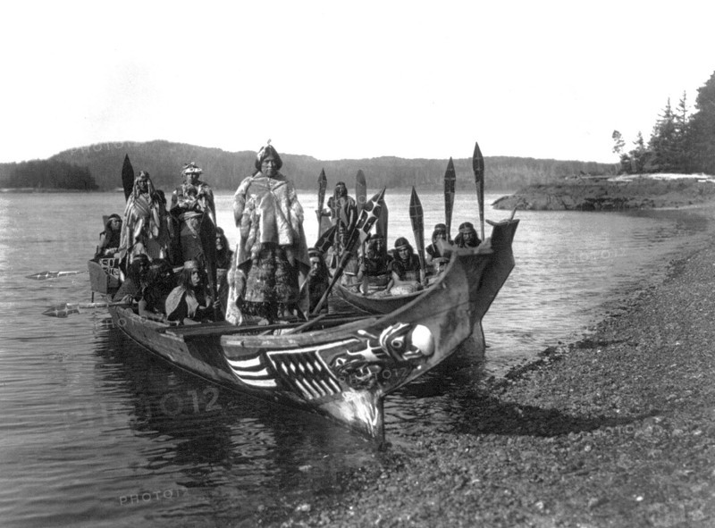 Edward S. Curits Native American Indians - Two canoes pulled ashore with wedding party, bride and groom standing on 'bride's seat' in the stern circa 1914.