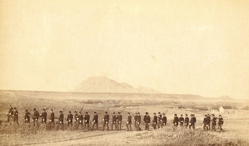 Company 'C,' 3rd U.S. Infantry, caught on the fly, near Fort Meade. Bear Butte in the distance 1890.