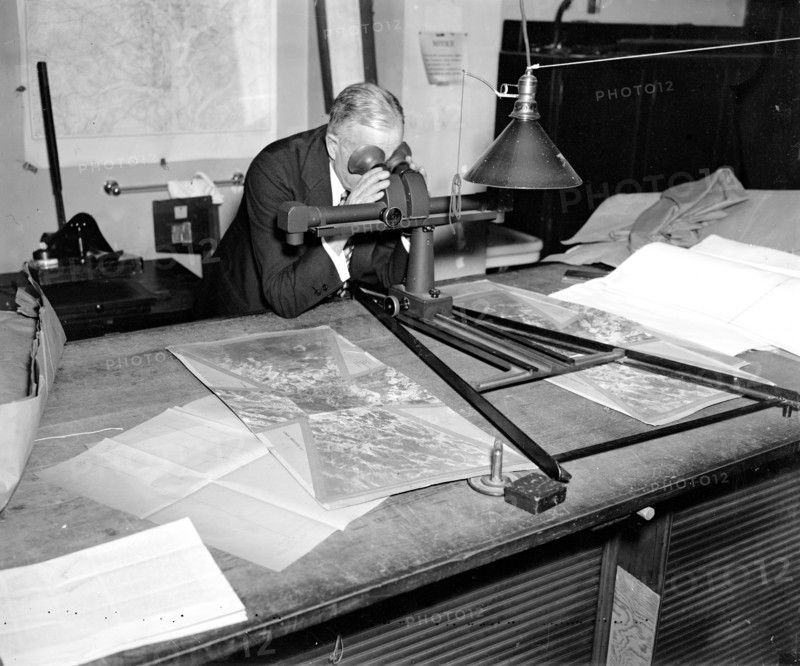 Geological Survey. Washington, D.C., March 13. Albert Pike using a stereoscope on a pair of photographs to bring out the relief and locate objects for a map circa 1937.