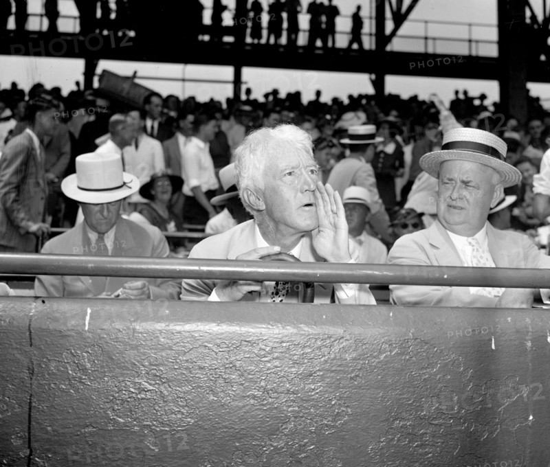 Kenesaw Mountain Landis, High Commissioner of baseball, assumes his characteristic pose for the cameramen as he views the 1937 all-star game in the Capitol, 7/7/37.