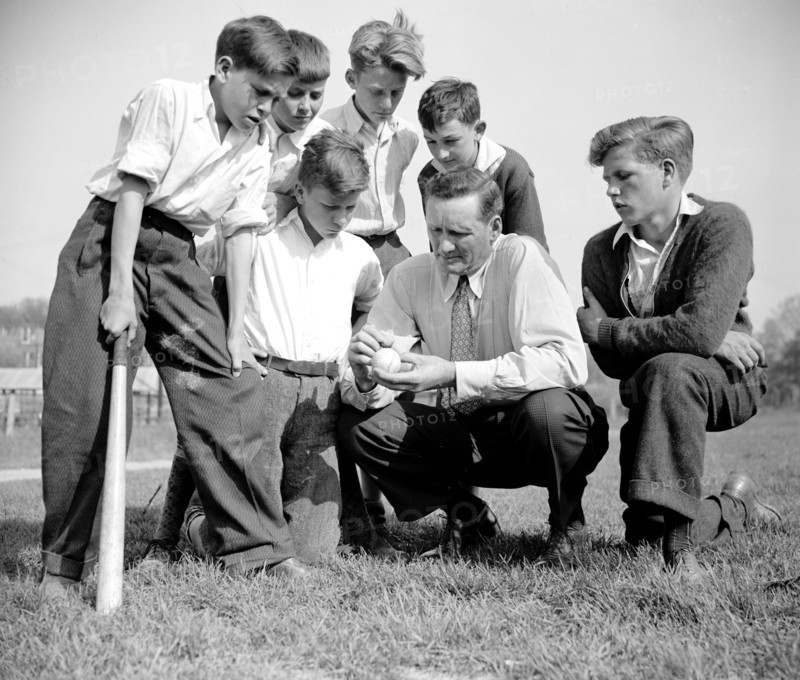 Hall of Fame pitcher Walter Johnson discussing the finer points of the game of baseball with young children circa 1940.