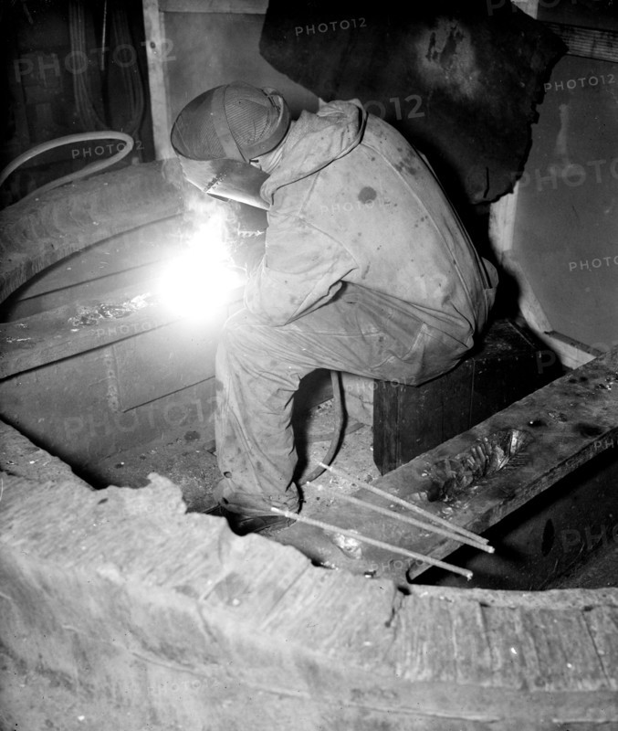 Factory worker welding a piece of metal circa 1936.