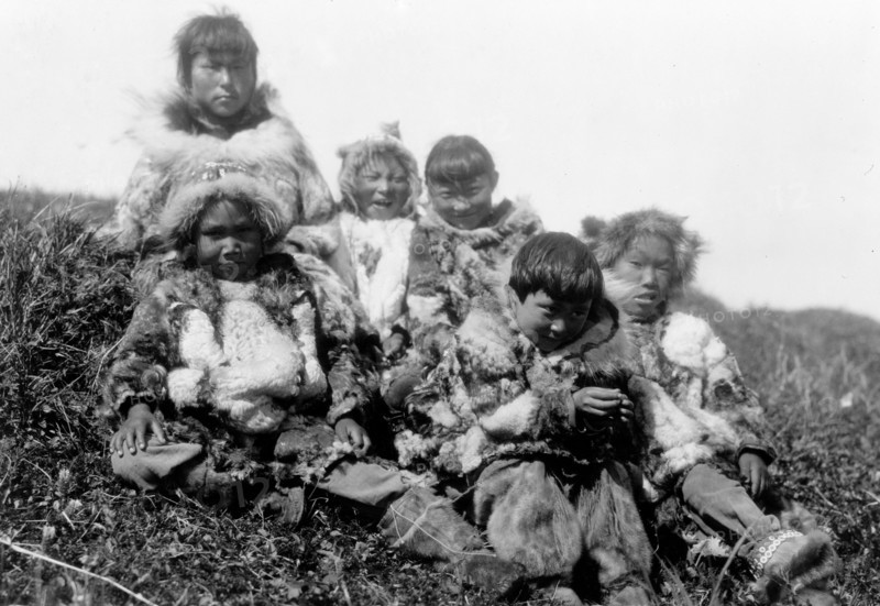 Edward S. Curits Native American Indians - Photograph shows six Nunivak children dressed in fur, sitting on hill circa 1929 .