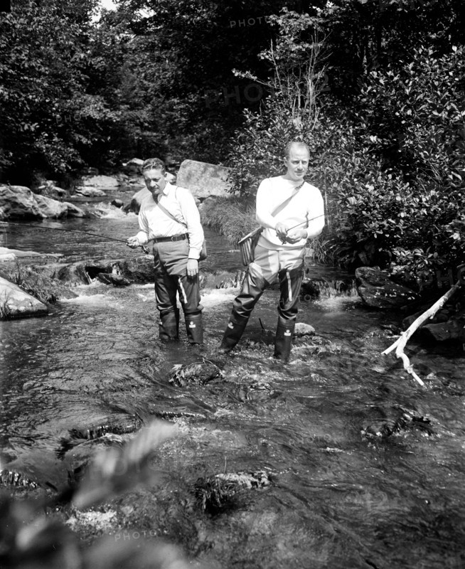 Two men fishing in a river circa 1932.