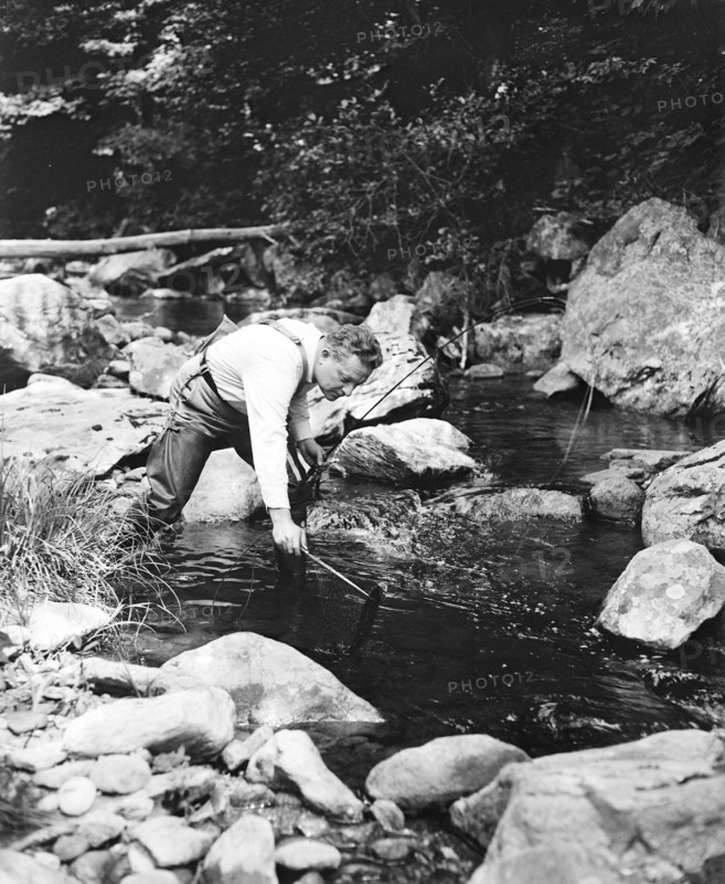 A man fishing in a river circa 1932.