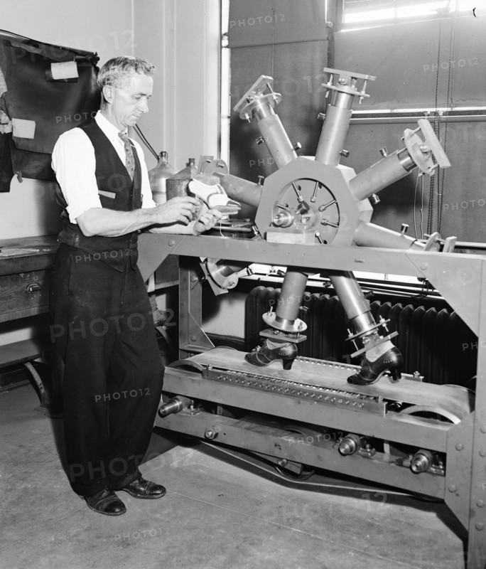 U.S. Government Waste - E.L. Wallace, acting Chief of the Leather Section of the Bureau of Standards, shown with the endurance shoe tester circa 10/24/1935 .