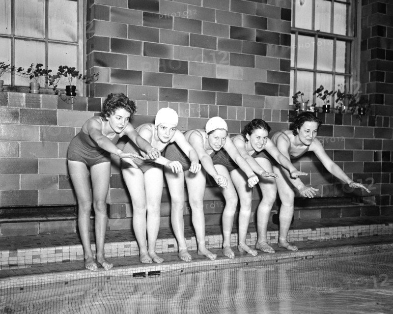 Women swimmers preparing to dive into a swimming pool circa 1936.
