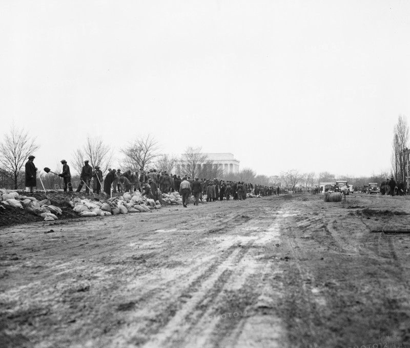 Men filling sandbags and placing them to protect an area of Washington D.C. during flooding of the  Potomac River, Washington, D.C. circa March 19, 1936 .