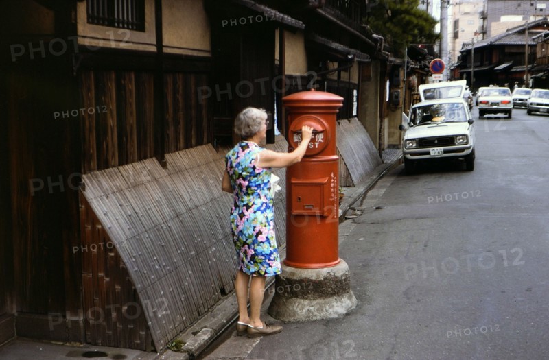 Woman mailing letters in a postal service mailbox in Kyoto Japan circa 1976.