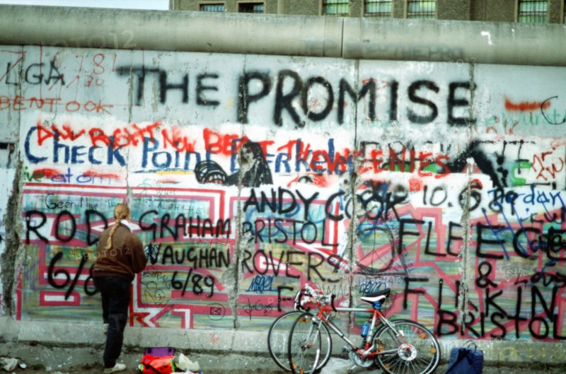 A West German woman attempts to chip off a piece of the Berlin Wall as a souvenir.   A portion of the Wall has already been demolished at Potsdamer Platz..