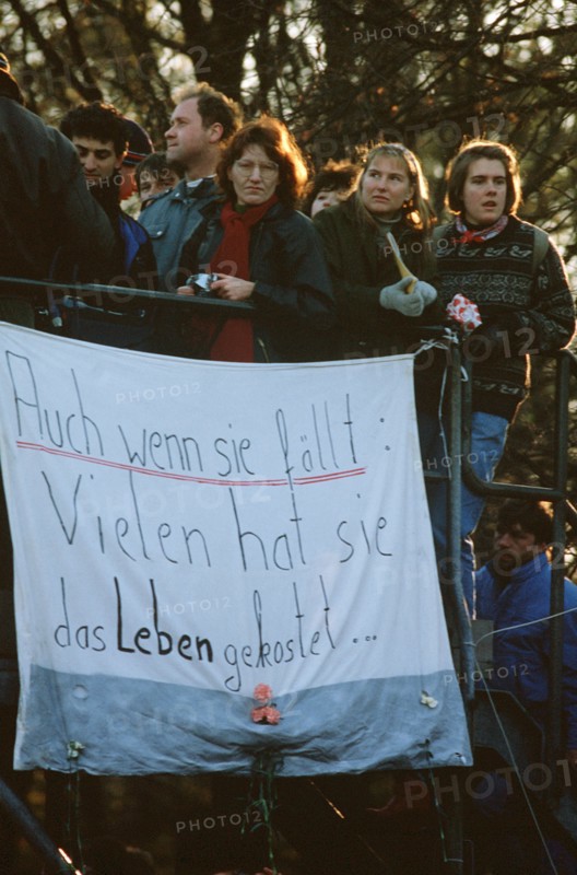 West German citizens display a banner as they maintain a vigil for the demolition of the Berlin Wall near the Brandenburg Gate.  A portion of the Wall has already been demolished at Potsdamer Platz..