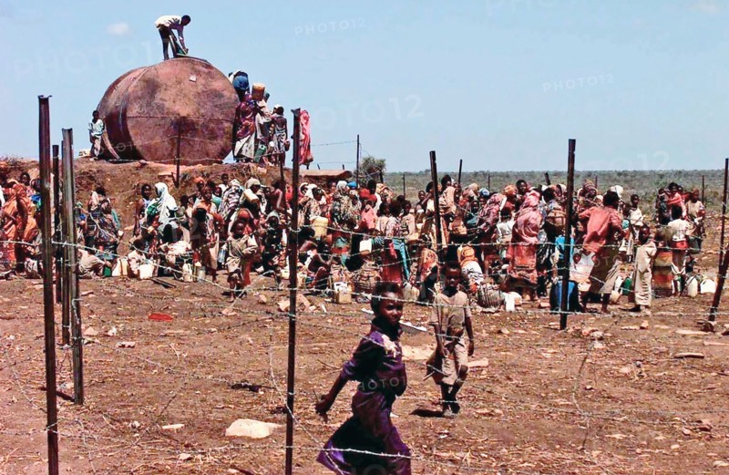 1993 - A Group of Somali refugees gathers behind barbed wire fence to get water from a well.