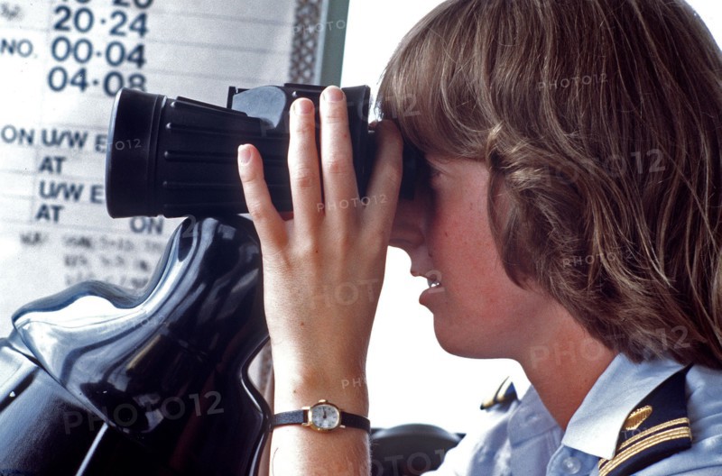 1980s Coast Guard - A female lieutenent junior grade officer piers through a pair of binoculars while on operations duty.