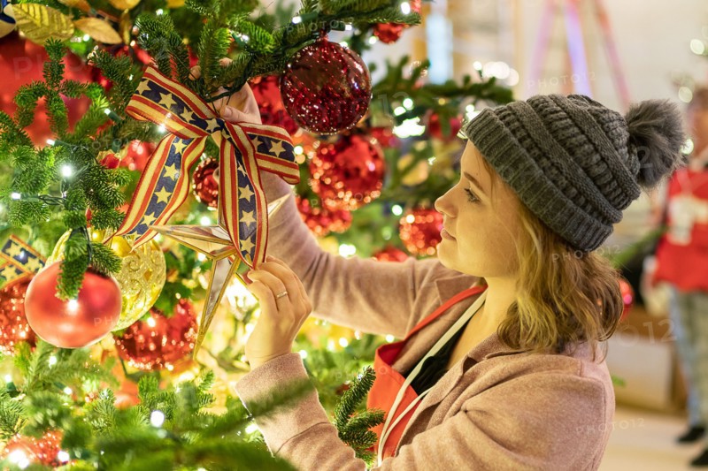 A volunteers decorates a tree in the East Room of the White House