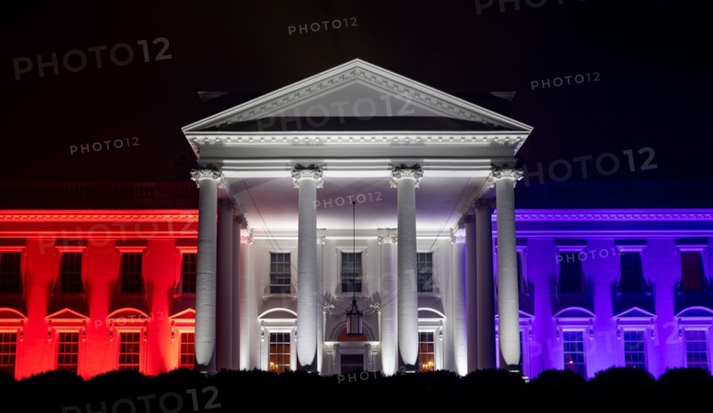 The White House North Portico is lit in red-white and blue lights
