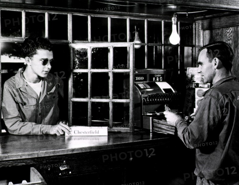 A visually impaired man purchasing a box of cigarettes at a store counter