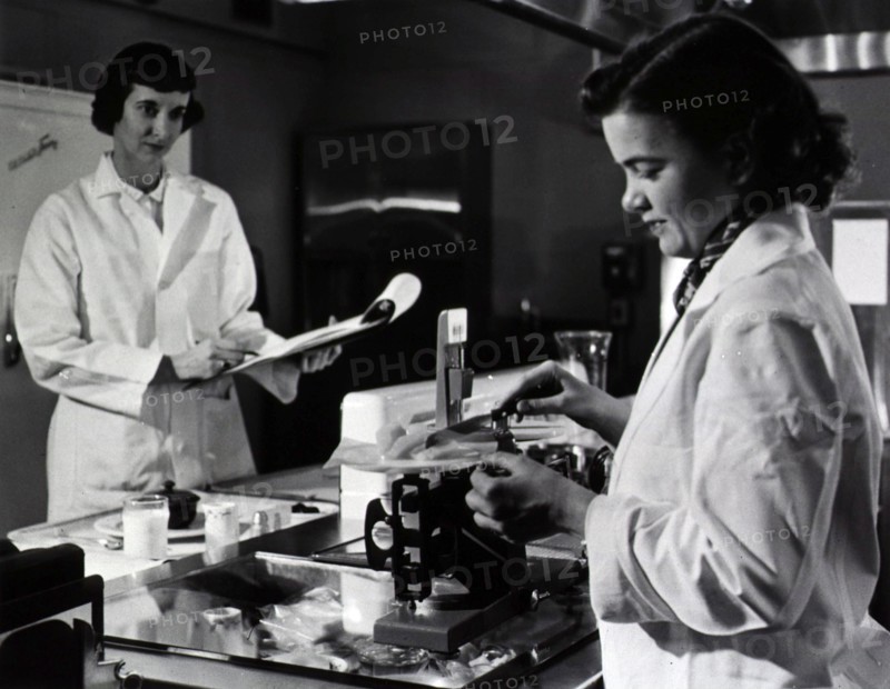 Two female dietitians weigh and measure foods before they are served to patients of restrictive diets.