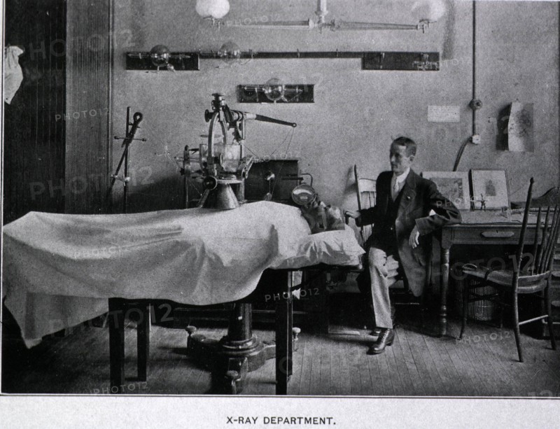 African American man is on a table covered with a sheet lying beneath an x-ray machine