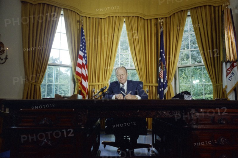 Gerald Ford signing presidential pardon of Nixon.