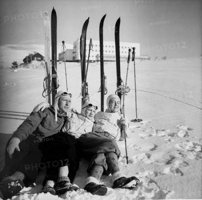 Three skiers chilling on snow, enjoying the sun in f