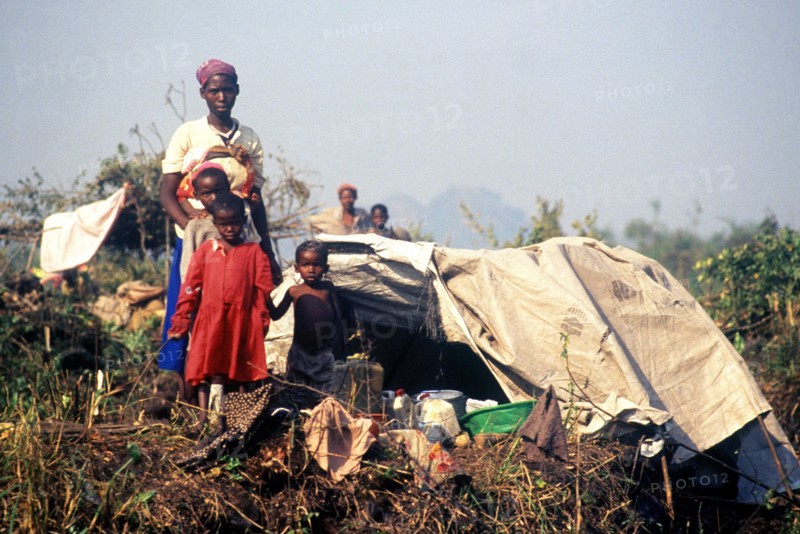 Rwandan family pose in front of their makeshift home