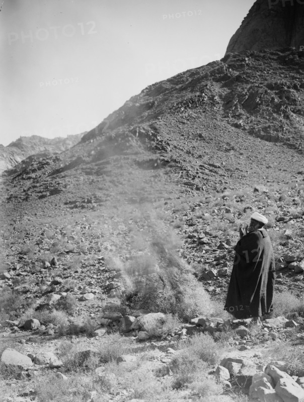 A man standing next to A burning bush silleh bush in Israel ca. 1900