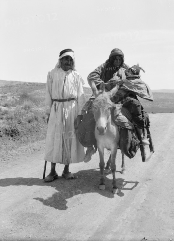 Bedouins in Israel, a woman and infant on donkey, a man standing ca. between 1934 and 1939
