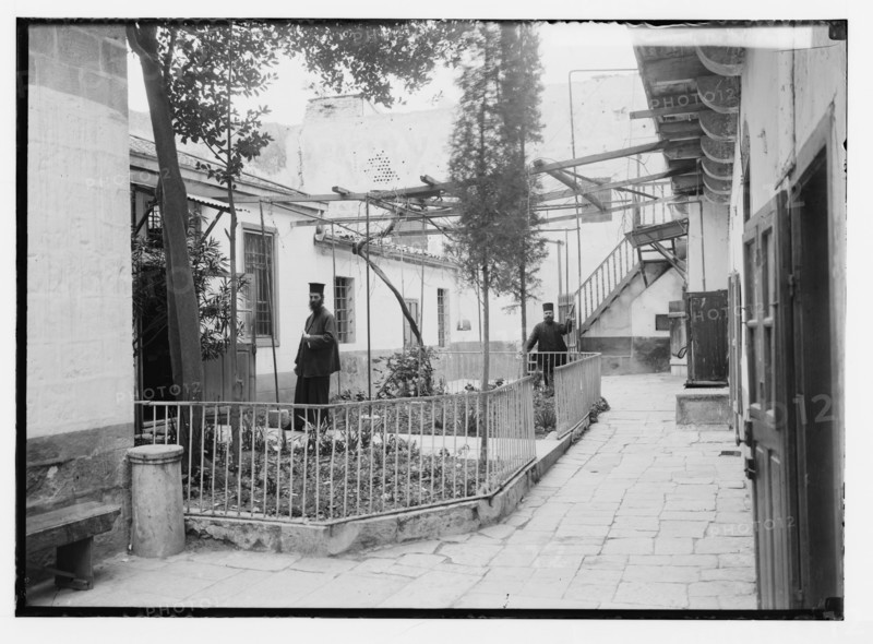 Two Orthodox priests at the Greek Convent near the Church of the Holy Sepulchre in Israel, the library exterior ca. 1920
