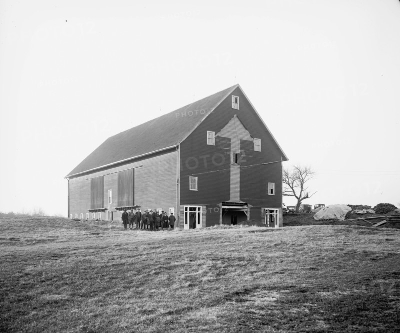 Men and women standing outside a barn  ca.  between 1910 and 1926