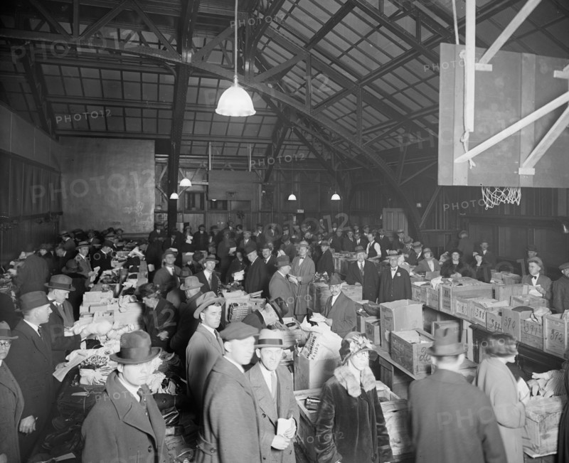 Men and women attending a dead letter sale being held in a gymnasium ca.  between 1910 and 1925