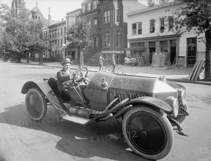 A man driving an early 20th century roadster car ca.  between 1910 and 1926