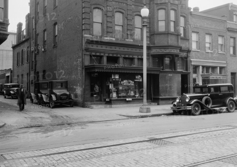 Man walking outside Tom's Lunch & Delicatessen shop ca. between 1910 and 1935