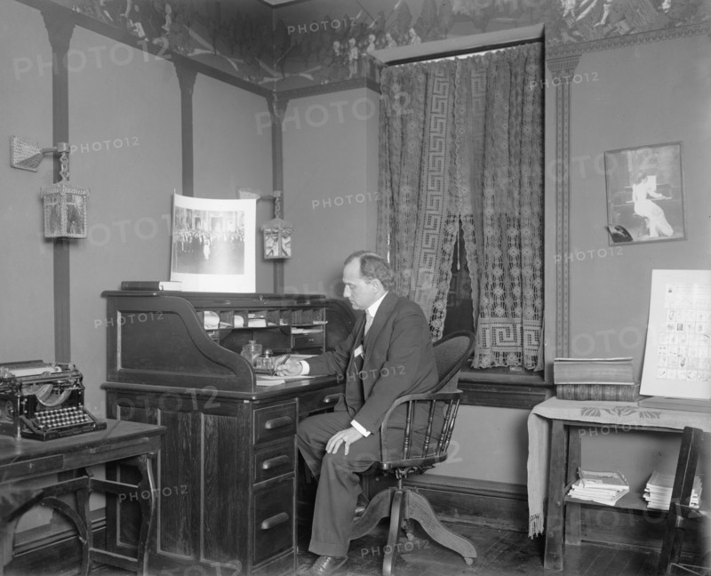 Raymond Dickey working at a desk ca.  between 1910 and 1925