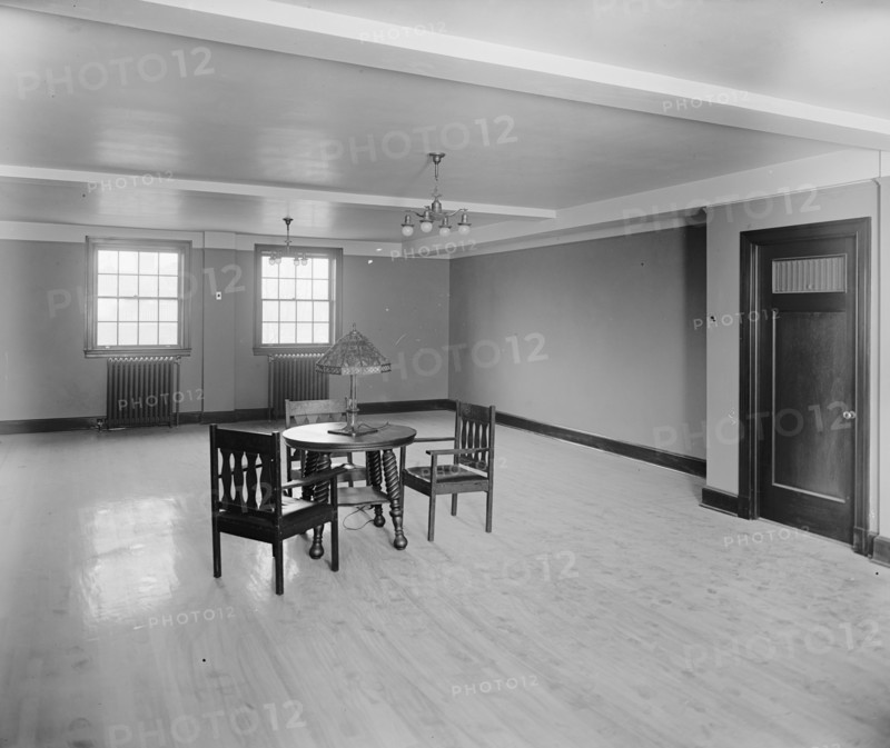 Three chairs and a table inside an otherwise empty room at the Jewish Community Center ca.  between 1910 and 1926