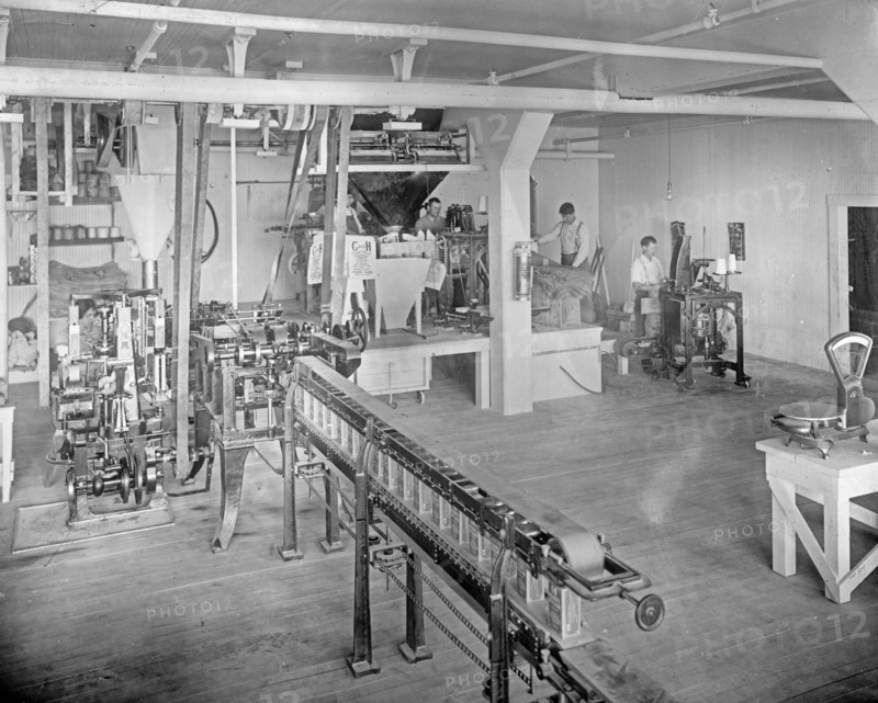 Carton Machine. Also showing filling and sewing 25 lb. sacks in background of picture, C&H Sugar Factory ca.  between 1910 and 1920